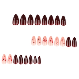 Red almond press-on nails set featuring bow designs and starry glitter details