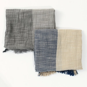 Close-up of color-block textured scarves with fringe detail in grey and blue tones