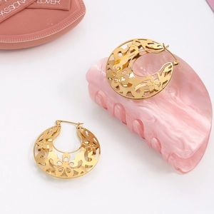 Détail de boucles d'oreilles vintage dorées avec motifs de dentelle baroque ajourée