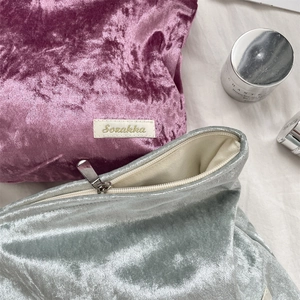Macro detail of velvet makeup bags with embossed texture and metal zipper closure