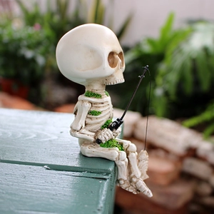 Detailed view of resin skeleton figurine with moss accents fishing in a garden setting