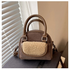 Detailed shot of brown faux suede handbag with beige plush faux fur pocket and metal D-rings