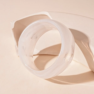 Detailed close-up of wide cream acrylic geometric bangle with smooth marbled texture