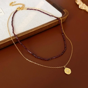 Gros plan d'un collier double épaisseur avec pendentif étoile et perles rouges