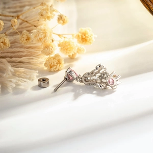 Silver heart lace earring with pink gemstone and hollow design on a floral background