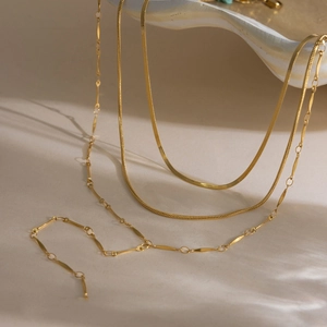 Detail of three-layer 18K gold plated stainless steel necklaces on a ceramic tray