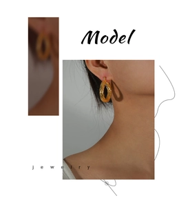 Detail of model wearing twisted golden textured hoop earrings with a minimalist design
