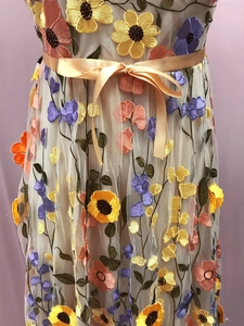 Détails de broderies fleurs 3D colorées sur robe en tulle beige avec un ruban champagne