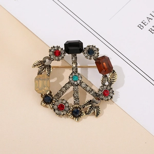 Detail view of retro alloy peace sign brooch with colorful rhinestones and leaf accents