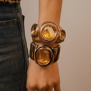 Detail view of woven metal wire cuff bracelets with large amber faceted crystal stones