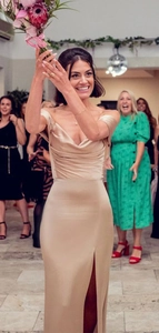 Detail of elegant champagne satin off-shoulder evening dress with a side slit detail
