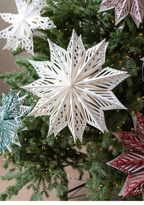 Detailed view of hollow paper star ornaments hanging on a Christmas tree in various colors