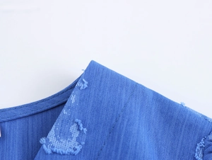 Détail du col en V avec bords effilochés sur une robe bleue au style vintage rétro