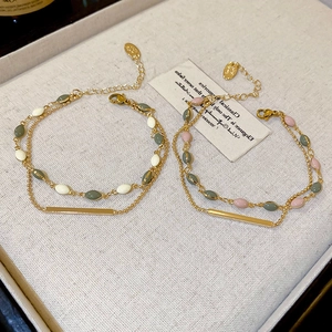 Detail of gold-plated double-layer bracelet with colorful beads and a brand tag