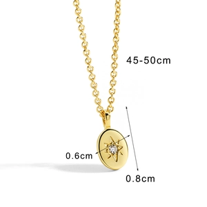Gold oval pendant necklace featuring a starburst engraving and clear gemstone on white background