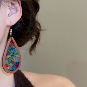 Close-up of geometric drop earrings with wood frames and colorful mosaic patterns