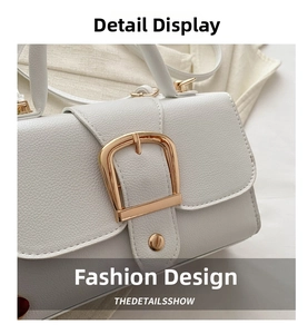 Close-up of white lychee texture leather with a polished gold horseshoe buckle detail