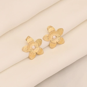 Detail von goldenen Blumensteckern mit weißer Perle auf Seidenstoff-Hintergrund