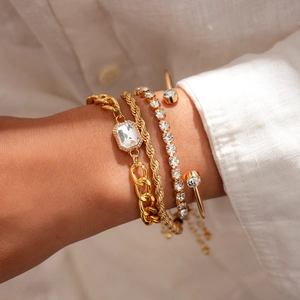 Goldenes 4-teiliges Metall-Armbandset mit Strasssteinen am Handgelenk einer Frau