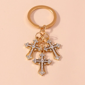 Detail of gold keychain featuring three shimmering rhinestone-encrusted cross pendants