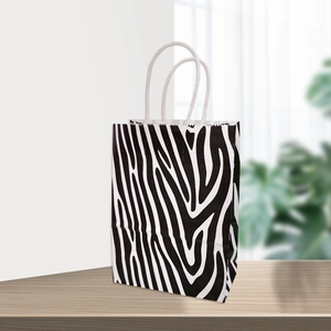 Détail d'un sac cadeau en papier kraft à motif zébré avec poignées en corde blanche