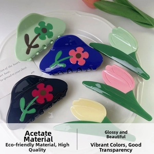 Detail of floral and tulip acetate hair claws in pastel colors arranged on a white ceramic tray