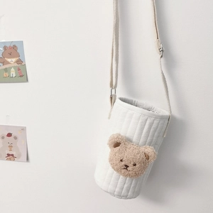 Detail of white quilted fabric water bottle bag with a brown teddy bear embroidery decoration