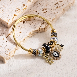 Dettaglio del bracciale a spirale dorato con ciondoli a forma di orso e cammeo su pietra