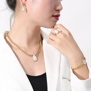 Detailed view of luxury gold jewelry set with teardrop shell pendants and CZ accents