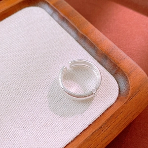 Macro detail of brushed silver adjustable ring with small zircon on a wooden display