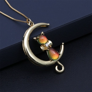 Chic golden moon and rainbow cat pendant necklace displayed on a textured jewelry box