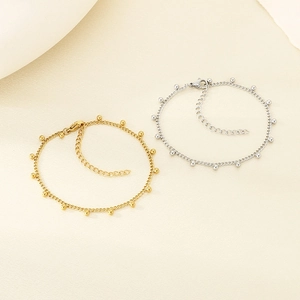 Minimalist stainless steel ball bead anklet set in gold and silver finish on beige texture