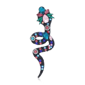 Macro detail of vintage snake brooch featuring colorful rhinestones on a dark metal base