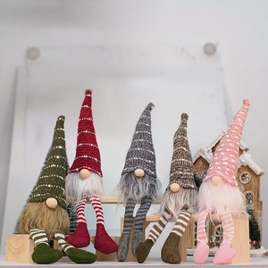 Group of five Christmas gnomes with striped long legs and colorful knitted hats on a bench