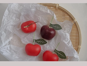 Primer plano de velas aromáticas de cereza rojas y moradas en una bandeja de bambú natural