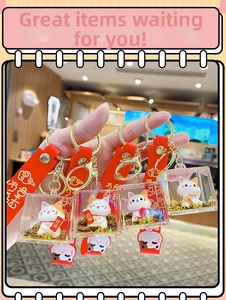 Macro detail of Maneki Neko keychain with golden glitter and red rubber wrist strap