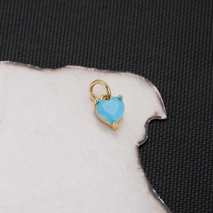 Macro shot of gold heart pendant with blue gemstone on vintage burnt paper background