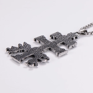 Close-up of vintage stainless steel double-cross pendant with distressed dot textures
