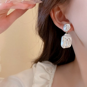Close-up of star-shaped pearl earrings featuring baroque style and gold metal accents