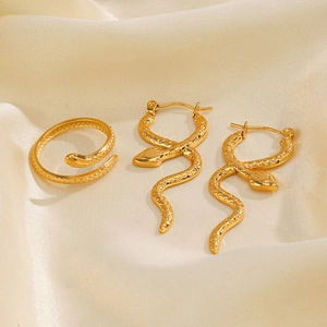 Vintage golden snake earring and ring set on beige silk fabric background