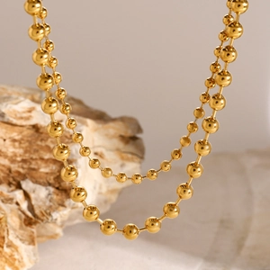 Close-up of polished 18k gold beaded necklace on natural stone display