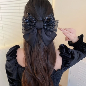 Detail of elegant black lace and sequin bow hair clip styled on a woman's bun
