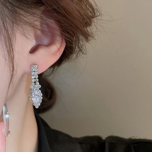Gros plan d'un mannequin portant des boucles d'oreilles en strass argentés en forme de U