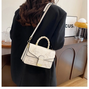 Détail du sac bandoulière crème avec broderie papillon et poignée tressée élégante