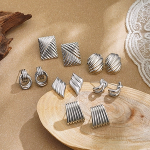 Set of six silver vintage geometric earrings with striped textures on a wooden display