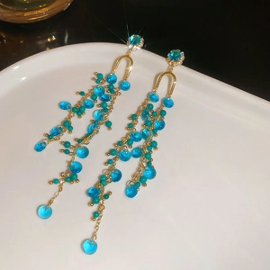 Detail of long gold tassel earrings with blue crystals and sparkling star effect