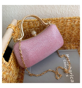 Close-up of pink glitter evening bag with golden wavy handle and diamond clasp detail