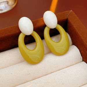 Macro detail of retro hollow oval earrings with amber resin drop in a premium jewelry box