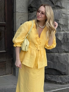Detailed texture of yellow linen V-neck ruffle top and matching maxi skirt set
