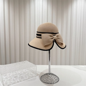 Chapeau de paille beige élégant avec ruban noir et nœud sur support métallique